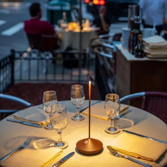 Runder Tisch im Freien mit Kerzenlicht, Weingläsern und Besteck, romantisches Abendessen-Setting.